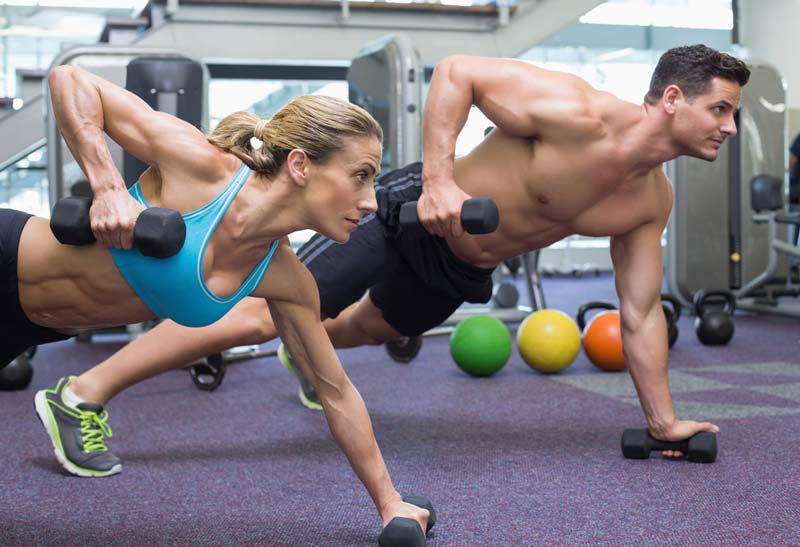 Two people working with weights in the gym